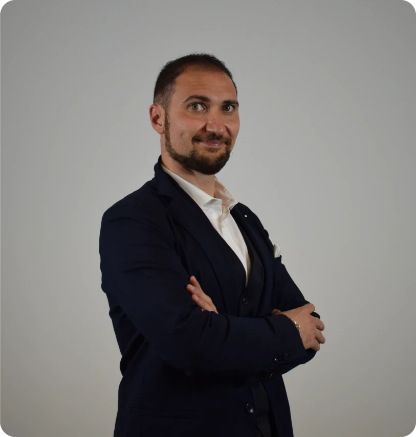uomo vestito elegante, mentre guarda in camera sorridente e con le braccia conserte